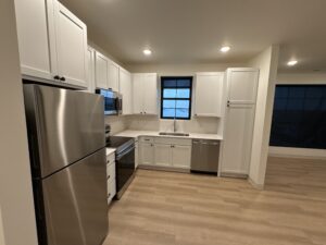 Modern apartment kitchen with white shaker cabinets and stainless steel appliances